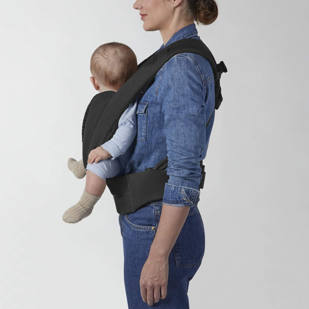 Lifestyle image of the Cybex Coya Carrier black front baby carrier worn by parent with baby secured inward.