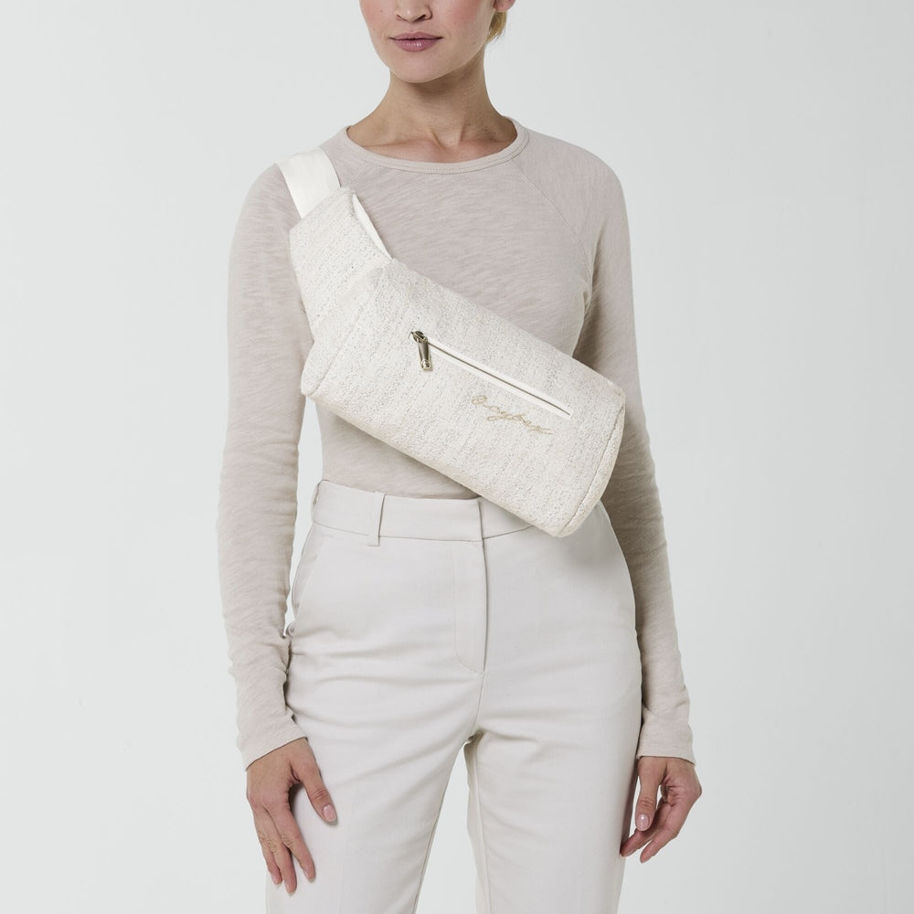 Lifestyle image of the Cybex Coya Carrier Boucle cream boucle cybex coya baby carrier worn as crossbody sling with zip pocket.