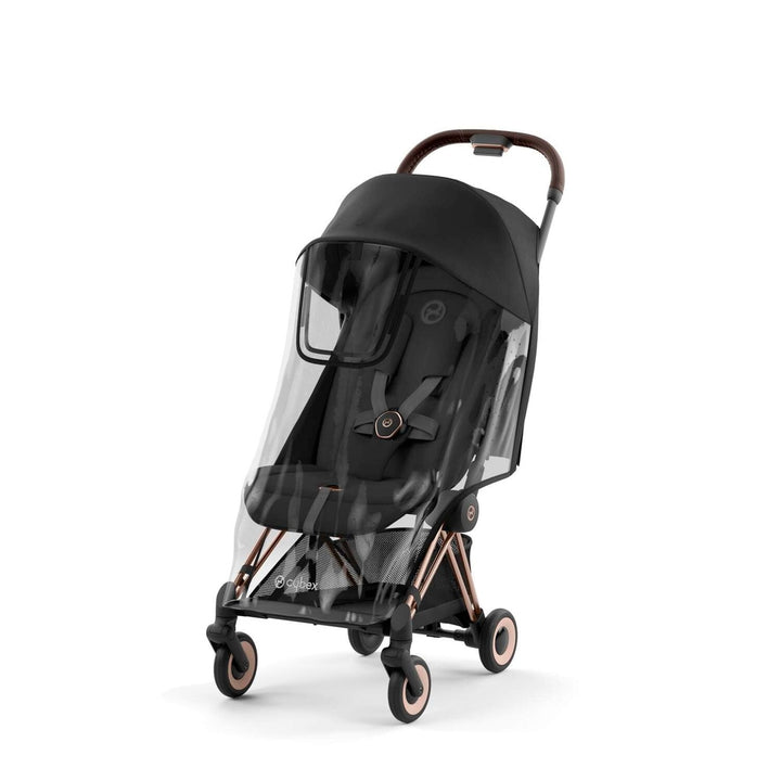 Lifestyle image of the Cybex Coya Rain Cover for stroller with clear canopy on black stroller and bronze accents.