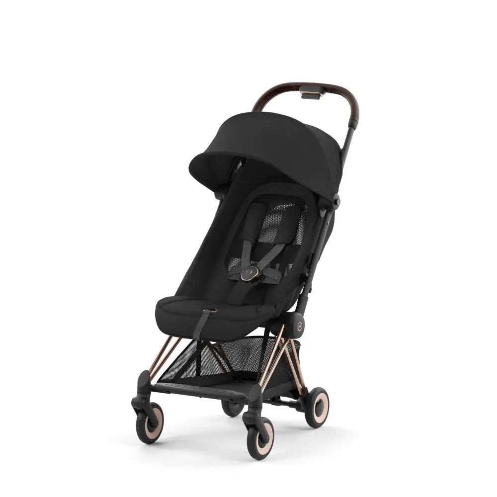 Lifestyle image of the Cybex Coya Rose Gold Frame Stroller in black with canopy and rose-gold frame.