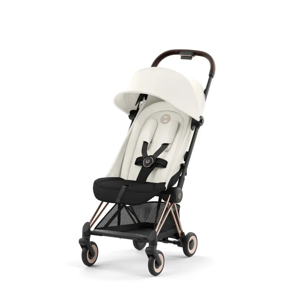 Lifestyle image of the Cybex Coya Rose Gold Frame Stroller with white seat and canopy, rose-gold frame visible.