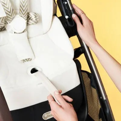 Lifestyle image of the Cybex Gazelle S V2 Stroller with white seat and black frame; hands adjust a frame clip.