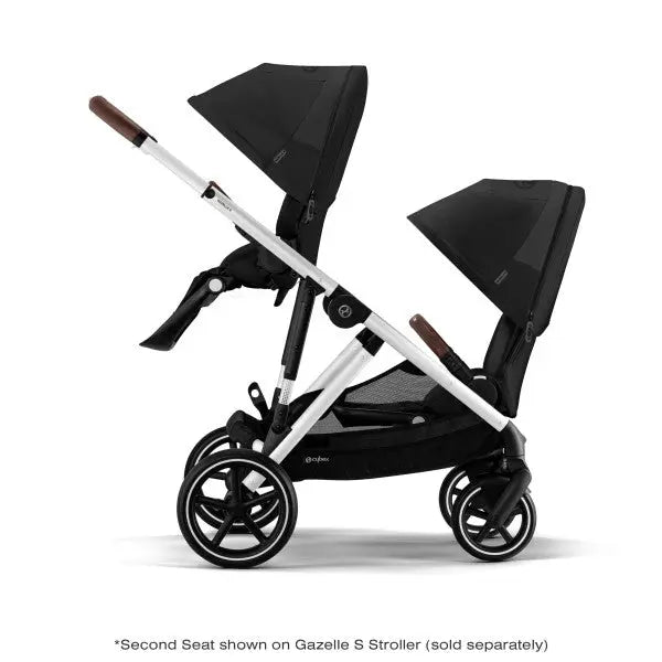 Lifestyle image of the Cybex Gazelle S V2 Toddle Seat double stroller in black, showing twin seats on a sleek silver frame.
