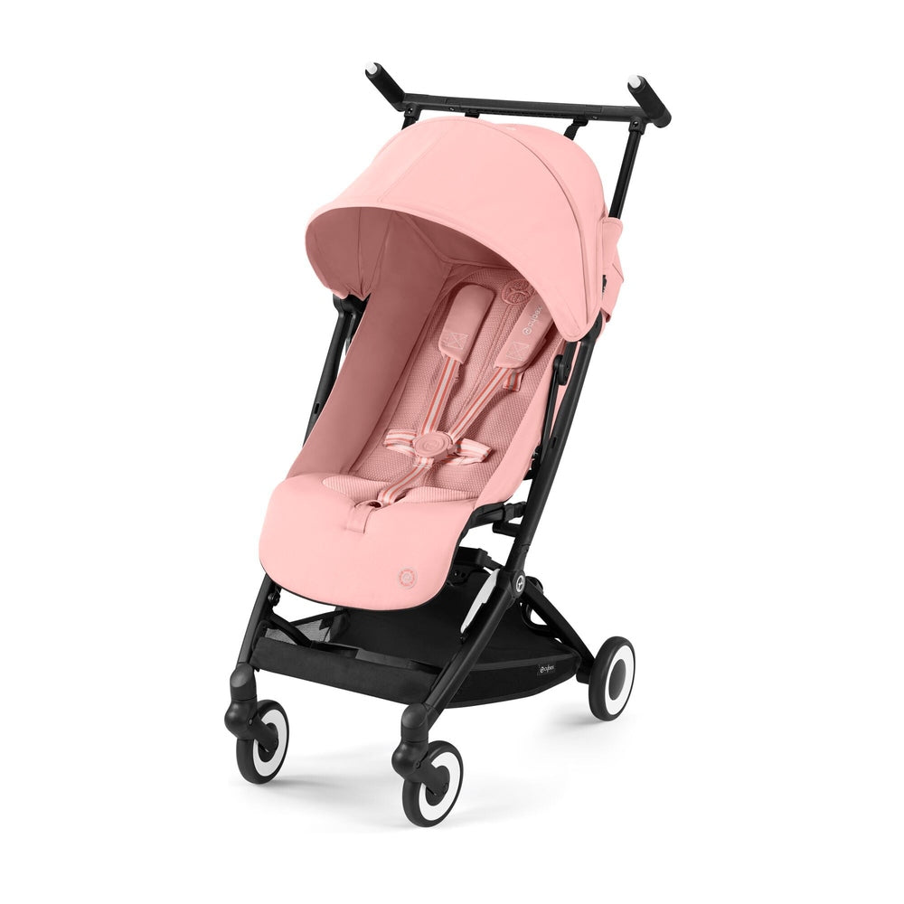 Lifestyle image of the Cybex Libelle 2 Stroller in pink with canopy and 5-point harness engaged on a black frame.