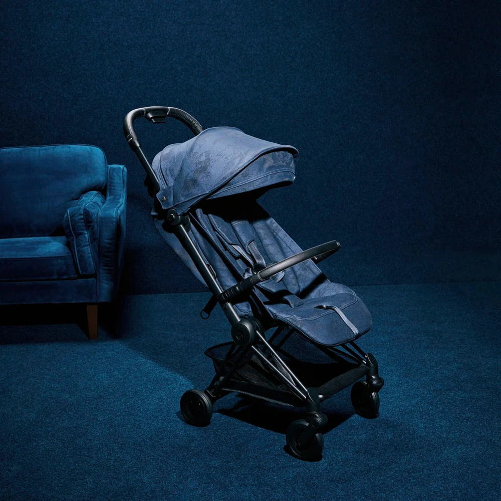 Lifestyle image of the Cybex Platinum Coya Compact Lightweight Stroller - Rebellious Luxury Denim Blue denim-blue cybex coya compact lightweight stroller with black frame and extendable canopy.