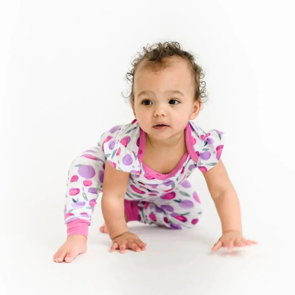 Little Sleepies Bamboo Pajama Set Plum; baby crawls on a white background in pink and purple polka-dot pajamas.