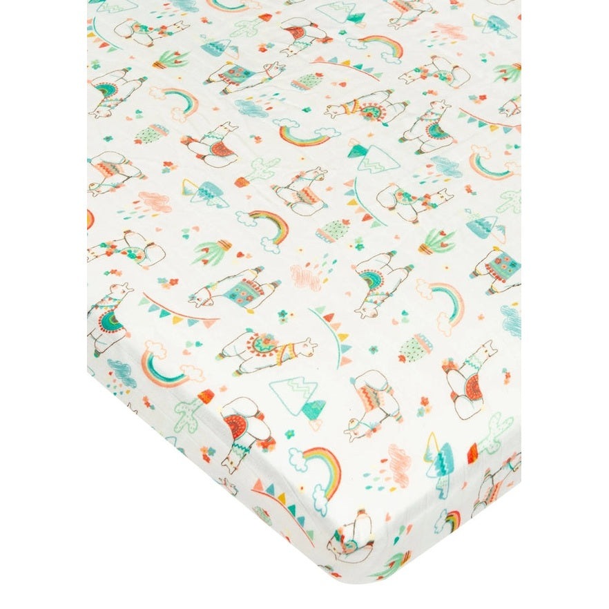 Loulou Lollipop fitted crib sheet in pastel llamas, rainbows and cacti, with elastic corners gripping the crib mattress