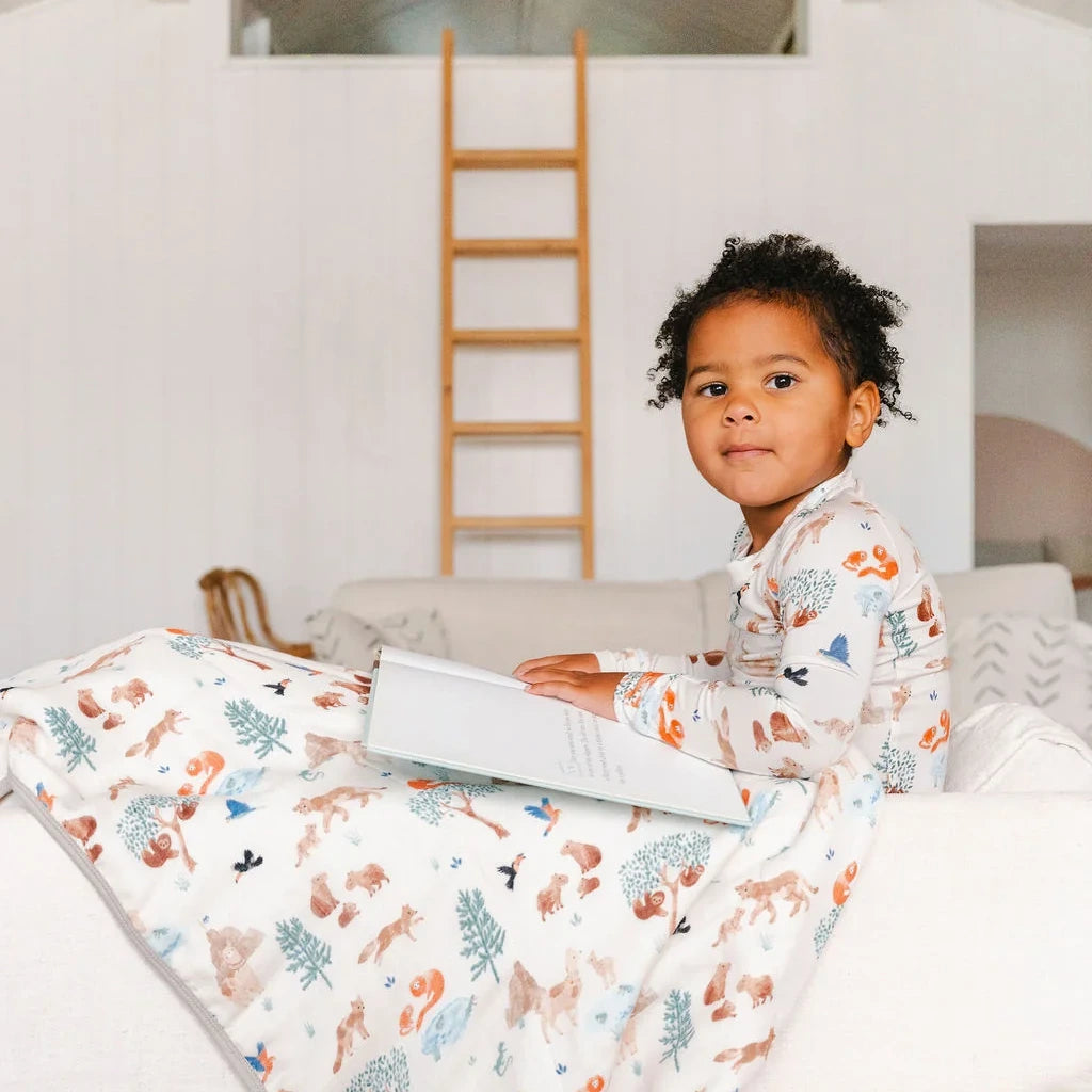 Loulou Lollipop Long Sleeve Pajama Set - Llama Adventures — child holding a matching quilt while wearing the pajamas.