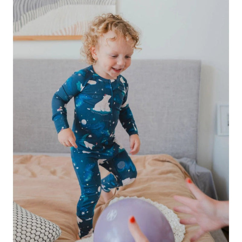 Loulou Lollipop Long Sleeve Pajama Set Stargazing Bear in blue space print; toddler jumps on bed with a purple balloon.