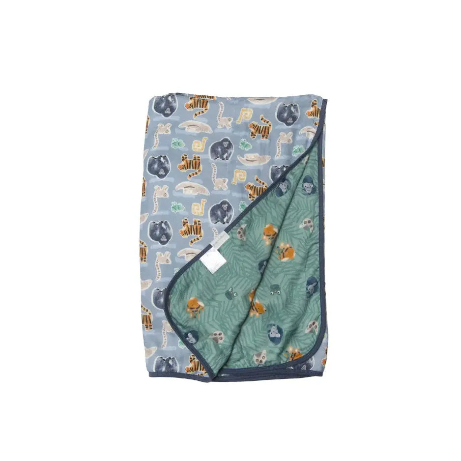 Loulou Lollipop Muslin Quilt Blanket, blue animal print with navy trim, green reverse shown halfway unfolded