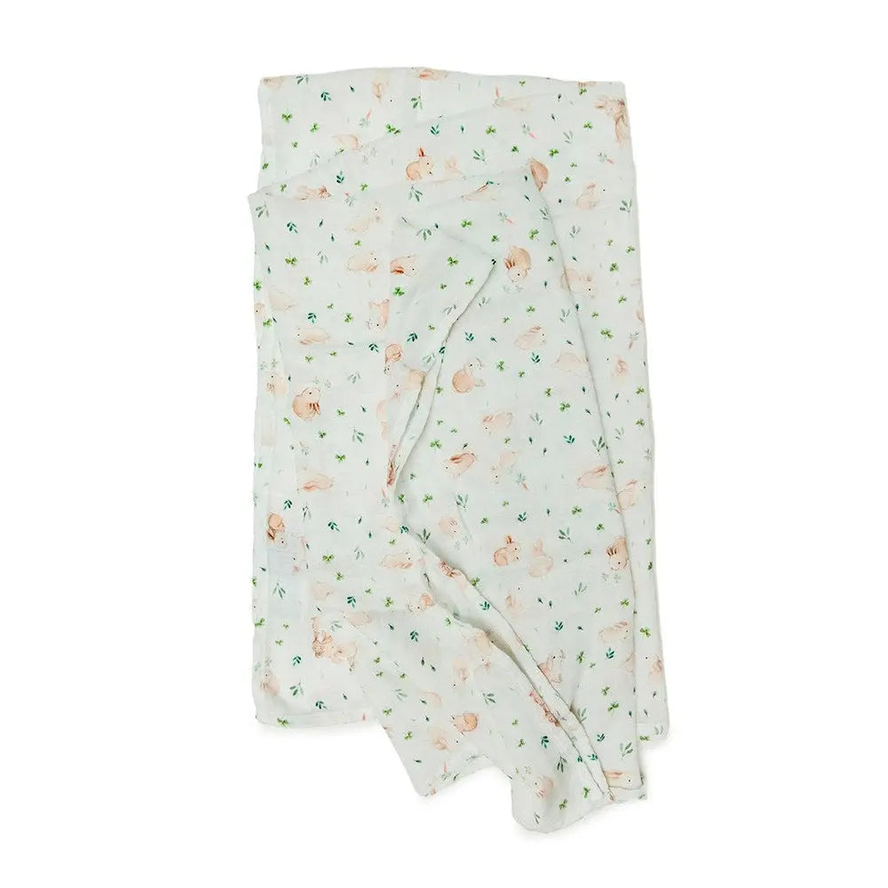 Loulou Lollipop Muslin Swaddle blanket, white with peach bunnies and green leaves, neatly folded for easy newborn swaddling.