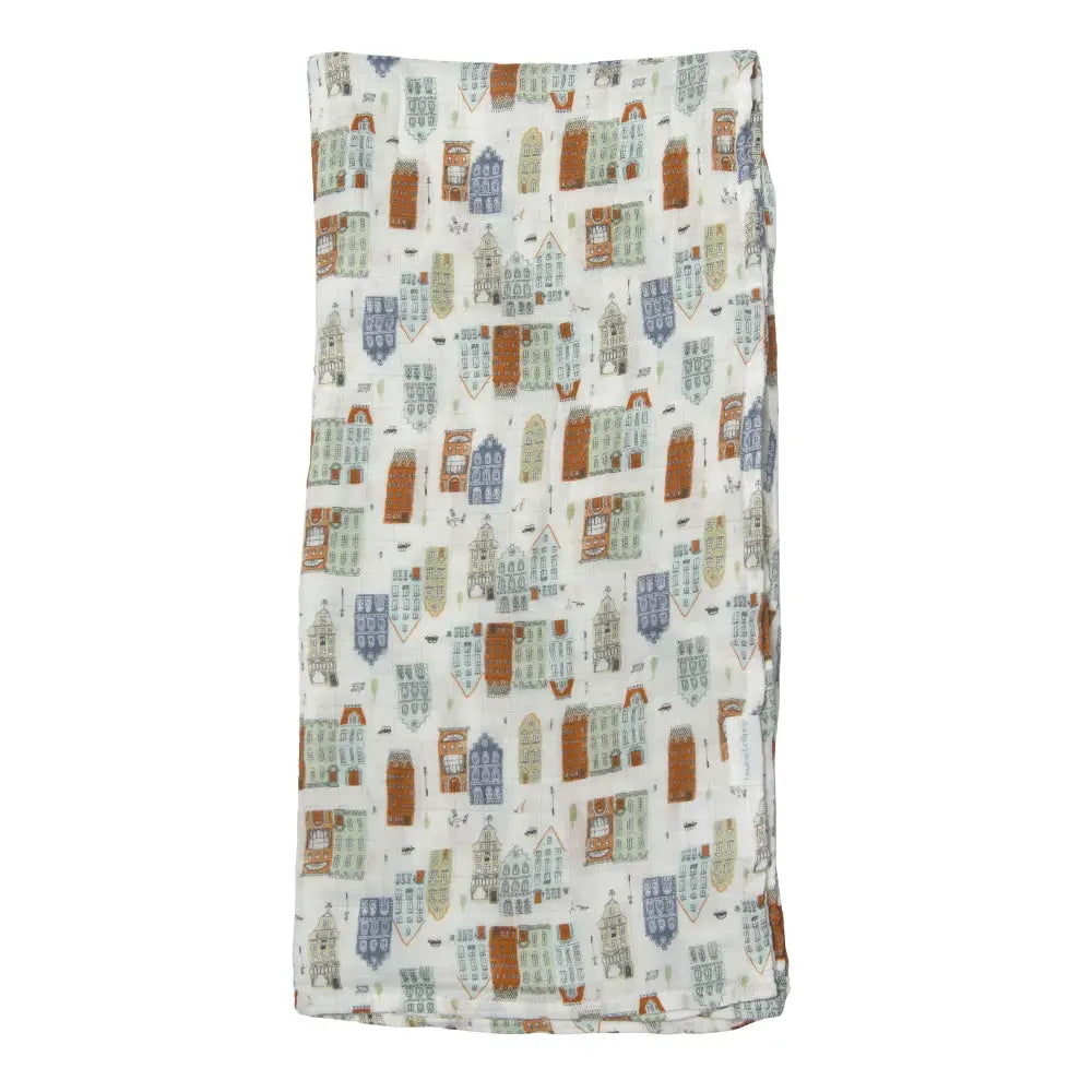 Loulou Lollipop Muslin Swaddle blanket spread flat, showcasing breathable fabric and colorful city-building print.