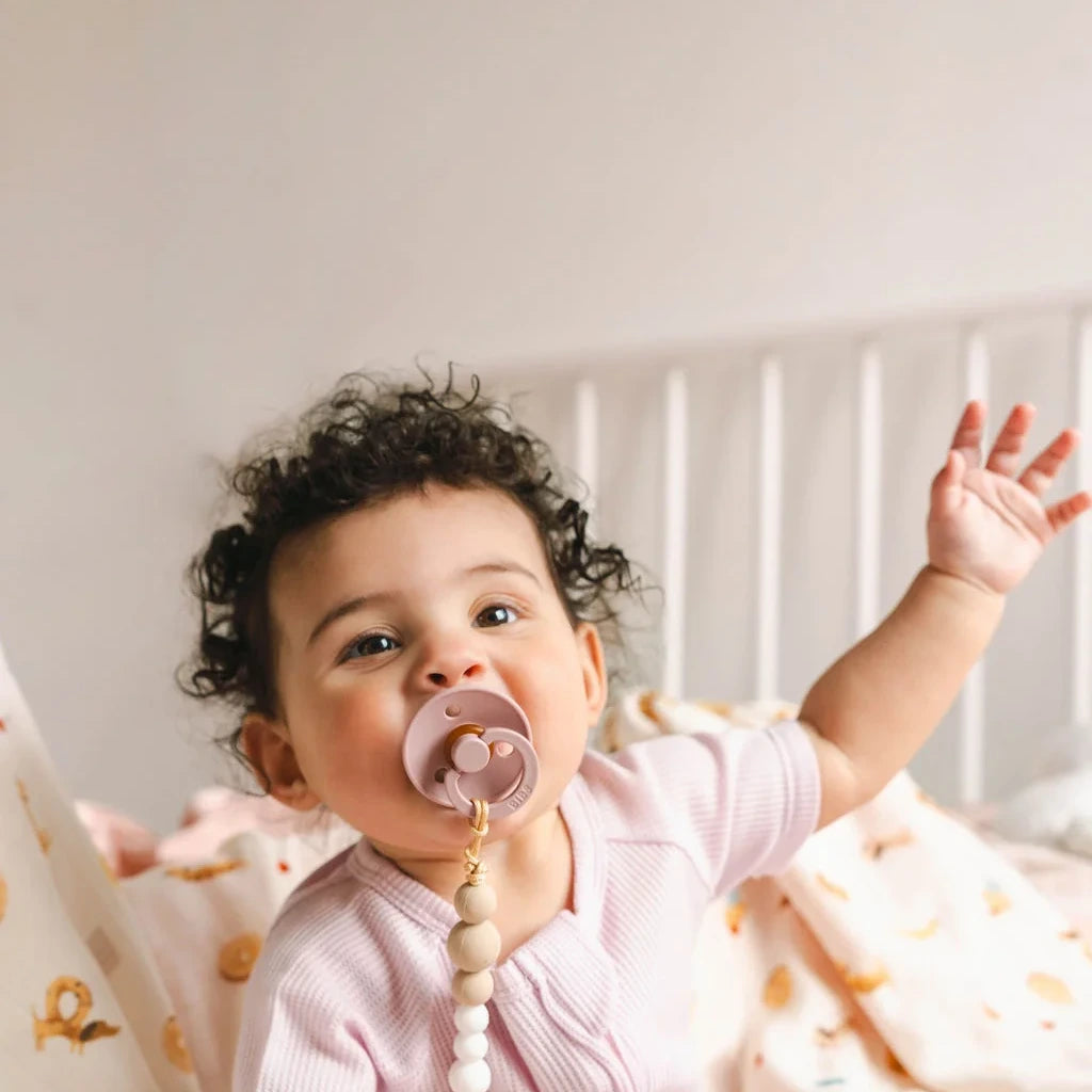 Loulou Lollipop OneC™ Silicone Pacifier Clip - White — baby with arms raised wearing the pacifier clip.