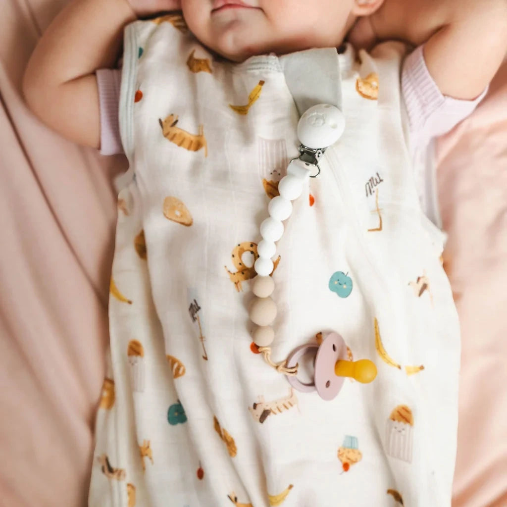 Loulou Lollipop OneC™ Silicone Pacifier Clip - White — close-up of the clip on printed baby clothing.