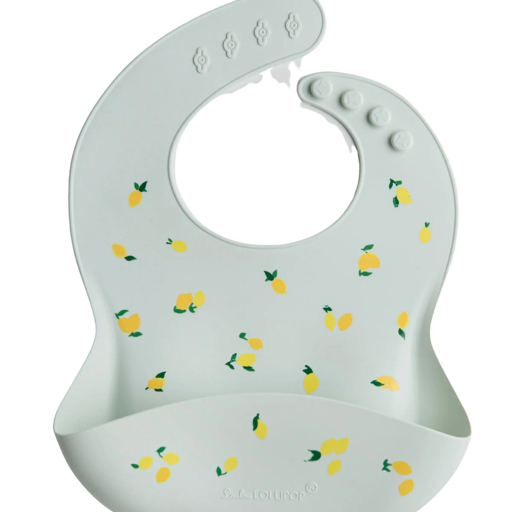 Loulou Lollipop Silicone Bib in pale blue lemon print; adjustable neck snaps and curved spill pocket catch drips.