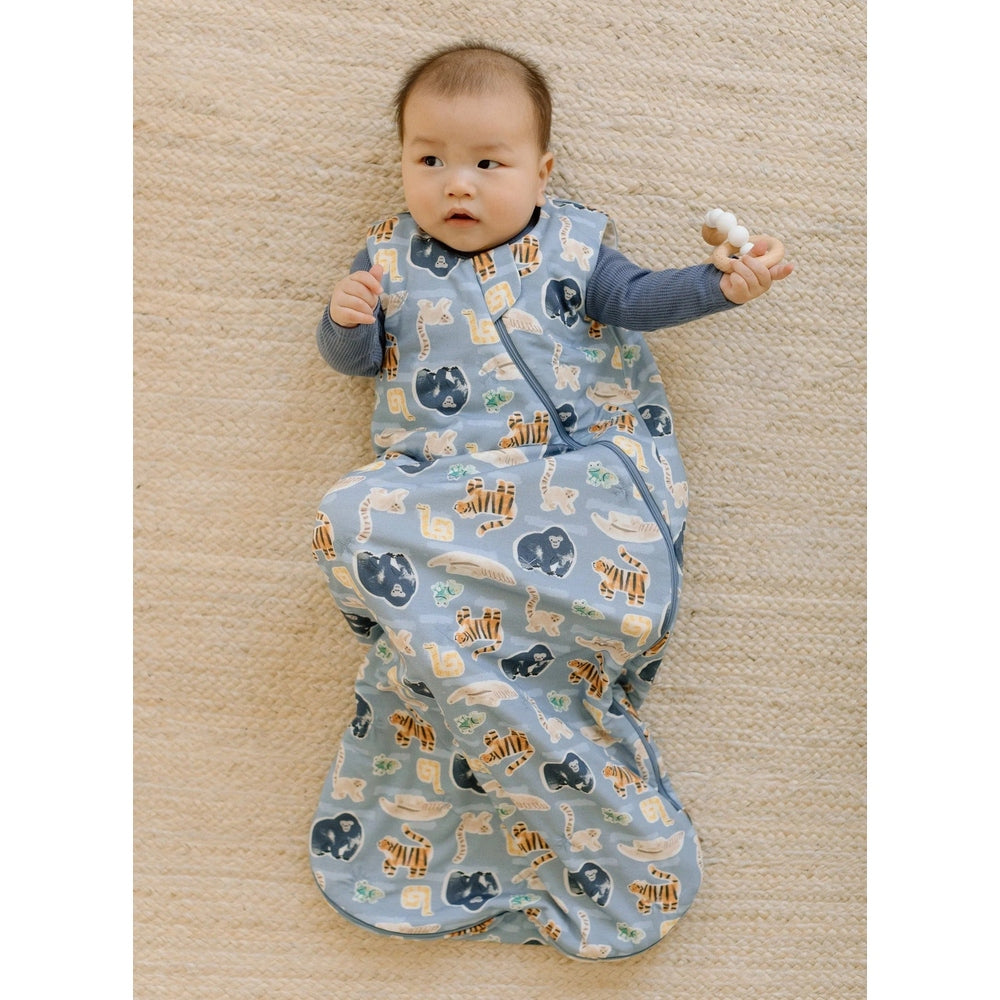 Loulou Lollipop TENCEL Sleep Bag 1.0 TOG Jungle Friends-baby lying on a rug in a blue sleep sack with a visible zipper.