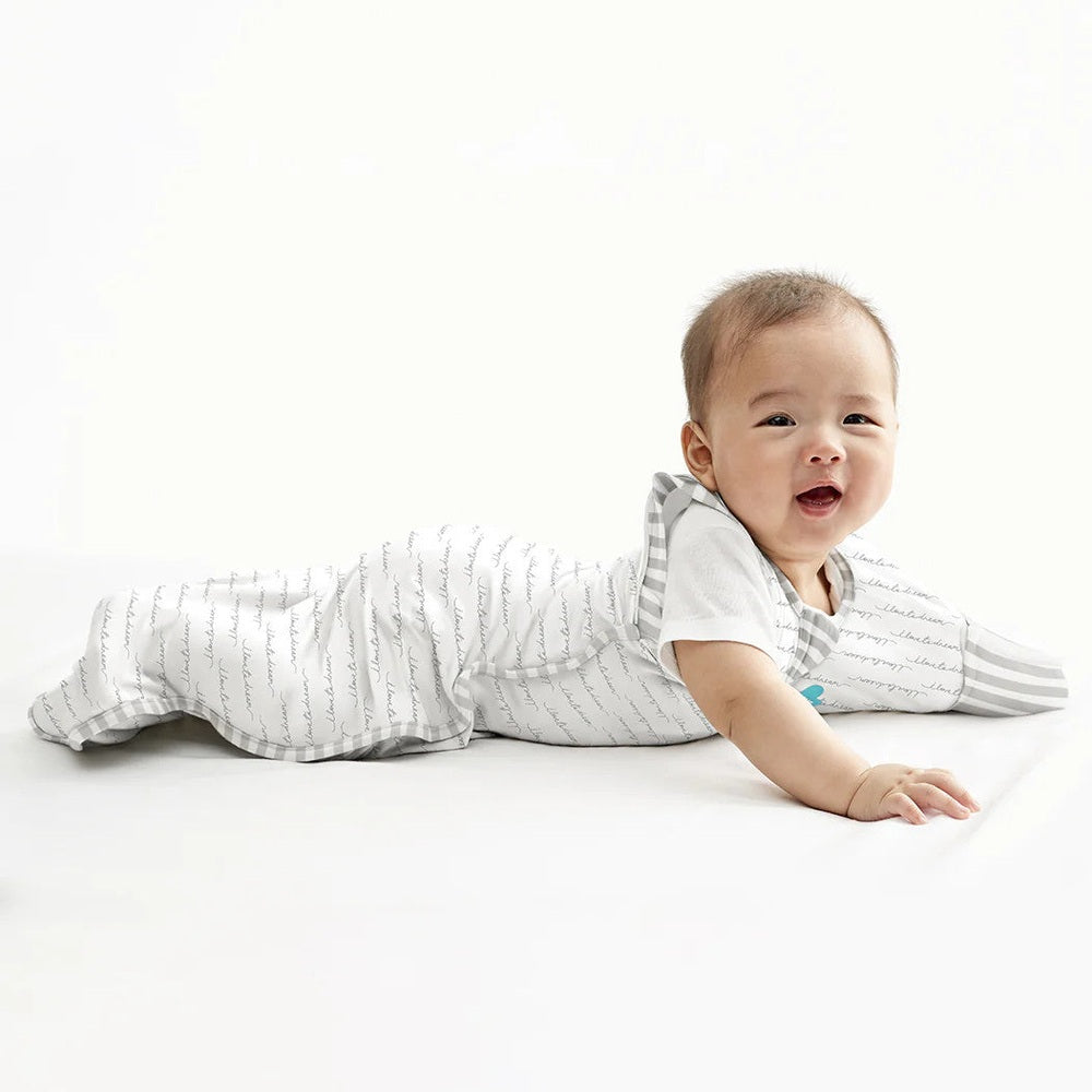 Love To Dream Swaddle Up Transition Bag Original Cotton 1.0 Tog in white; baby lying on tummy in the swaddle.