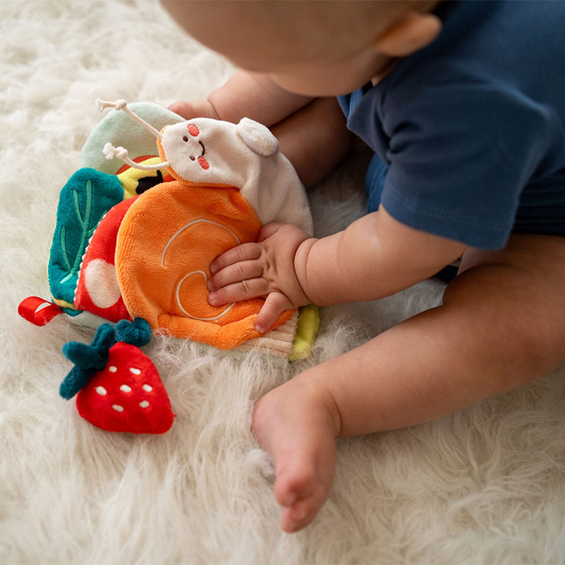 Manhattan Toy Silly Snail Sensory Book - baby touching the orange snail shell