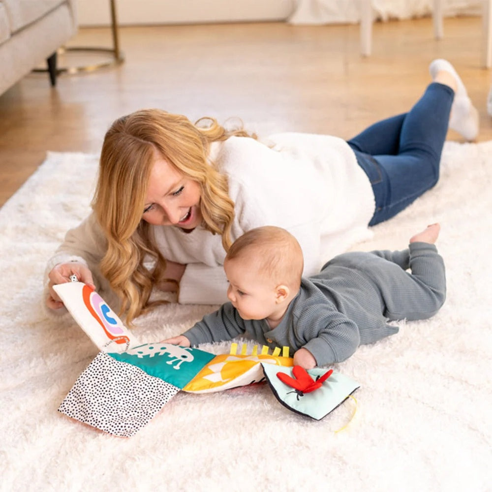 Manhattan Toy Wimmer Seek & Peek Book, fabric baby activity book, mom and baby play on a rug with colorful flaps.