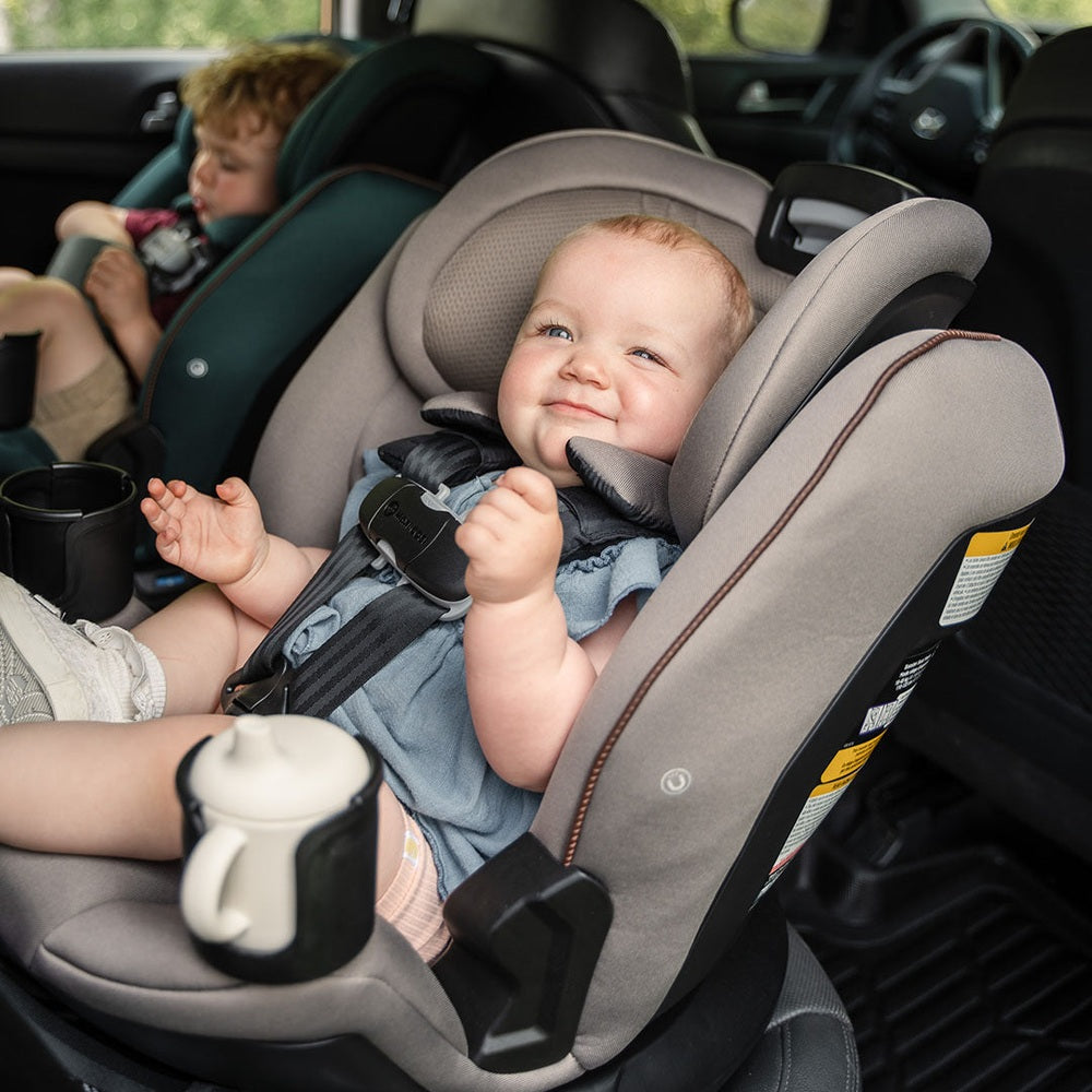 Maxi-Cosi Andi 360 rotating all-in-one convertible car seat in gray with harness; two kids seated in car seats.