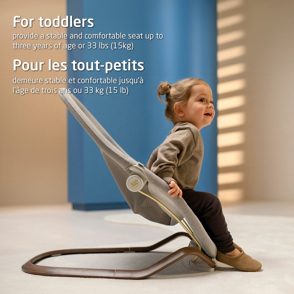 Toddler in light gray mesh baby bouncer in a modern room