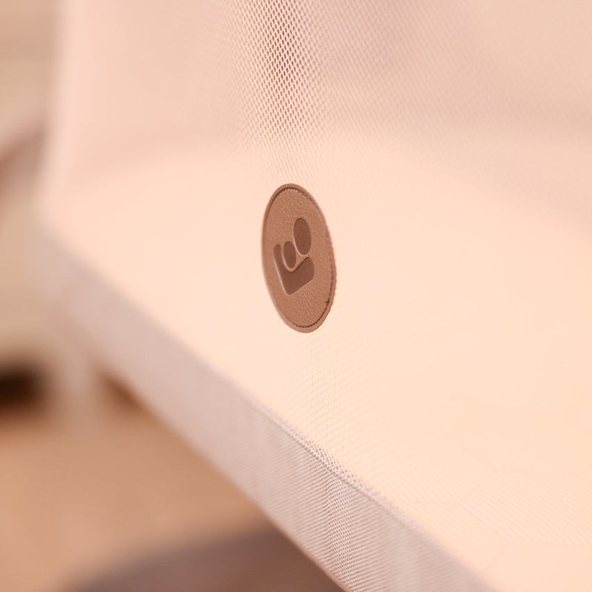Maxi-Cosi Iora bedside bassinet exterior close-up showing brand logo on white fabric

