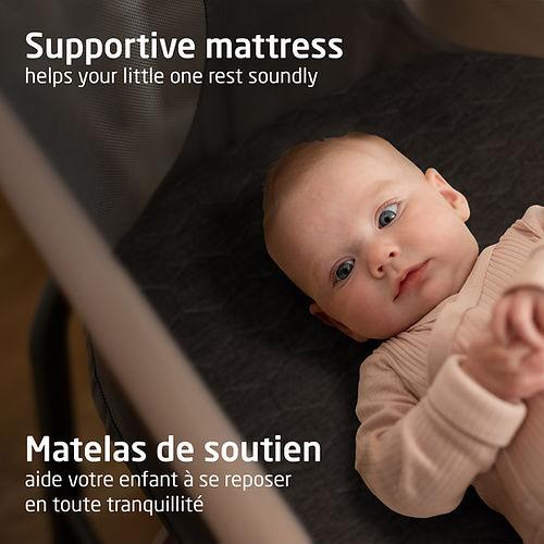 Maxi-Cosi Iora bedside bassinet with supportive mattress; baby rests calmly on soft fabric.