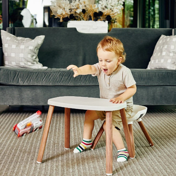 Maxi Cosi Moa 8-in-1 high chair; toddler seated at a white round table with wooden legs in a living room