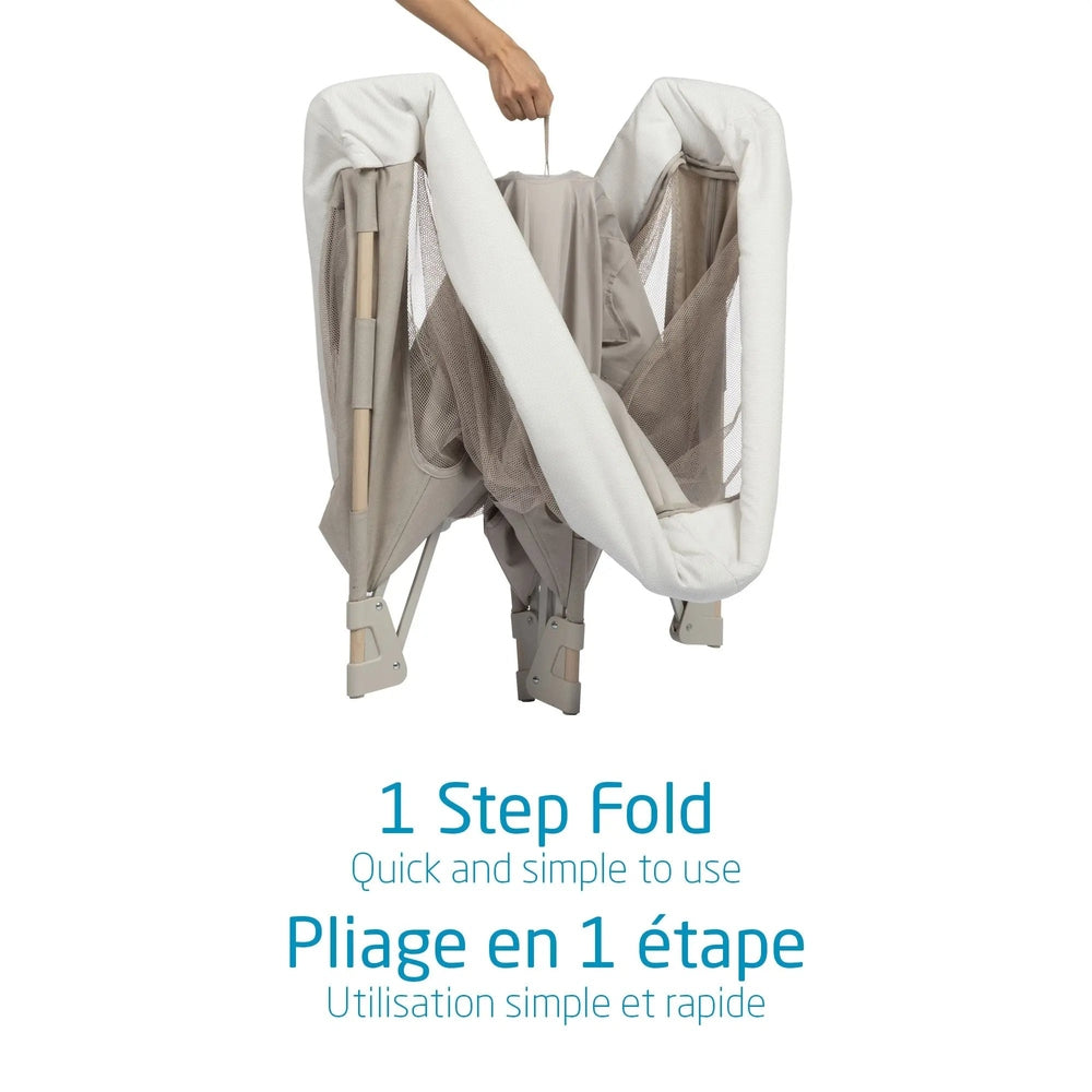 MAXI COSI Swift Playard beige fabric with mesh, folded by one hand to show its quick 1-step fold