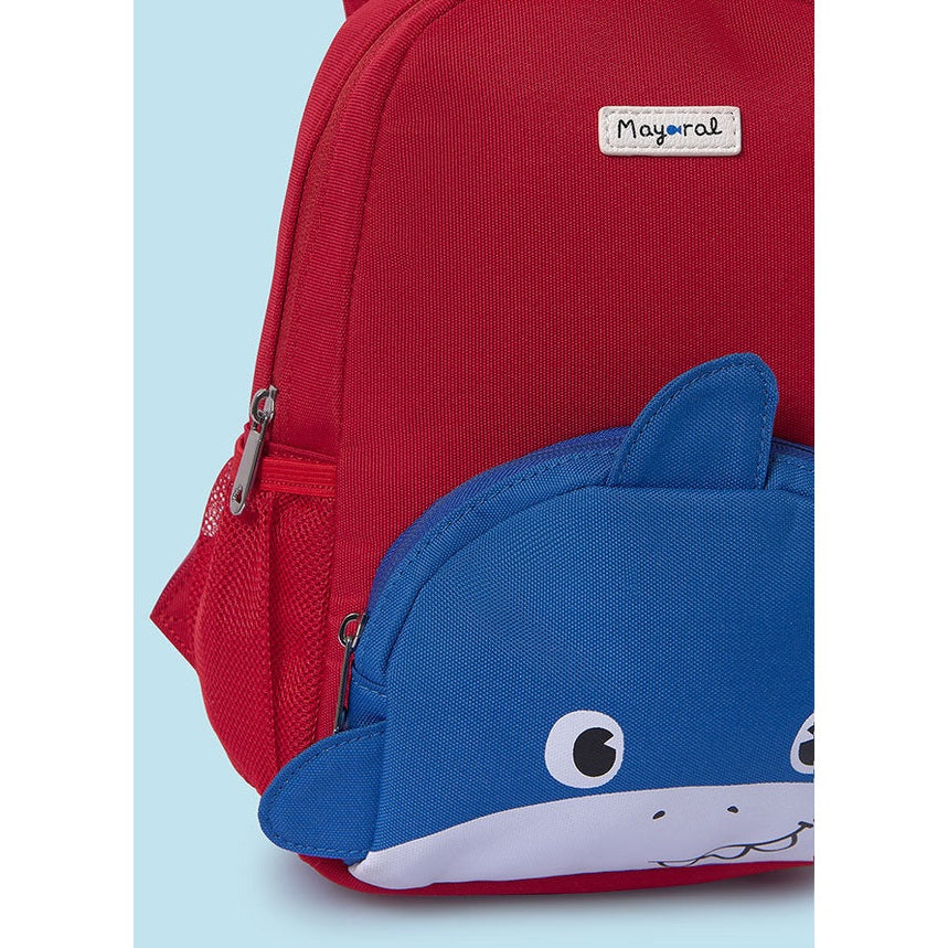 Red backpack with a blue shark-shaped pouch on a light blue background