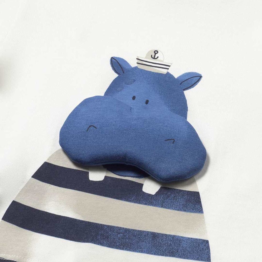Blue hippo-shaped pillow with a striped blanket on a white background