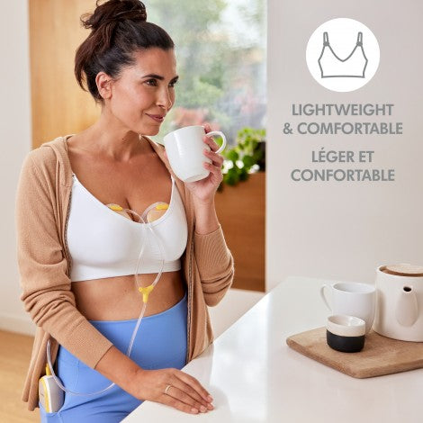 Medela Freestyle hands-free double electric breast pump in use; white unit with tubing and cups