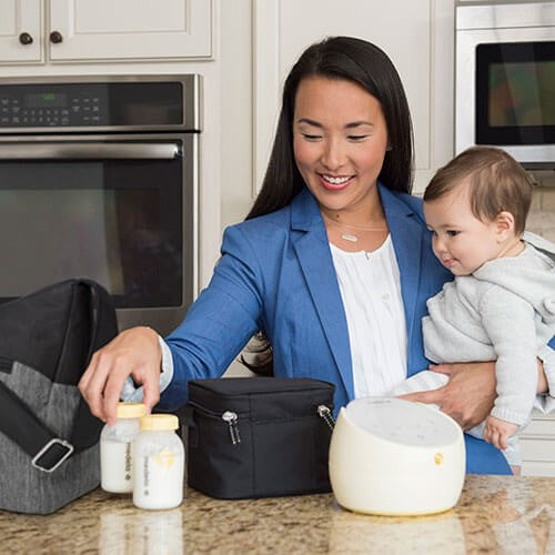 MEDELA Medela Sonata Smart Breastpump on kitchen counter as cheerful mom prepares bottles for baby.
