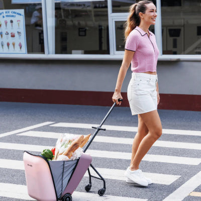 Micro Luggage Eazy Allrounder pink rolling suitcase pulled by a woman in a pink knit top and white shorts