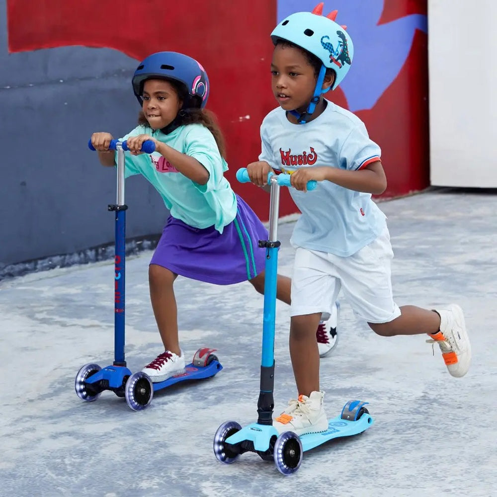 Micro Maxi Foldable Deluxe LED Scooter: blue scooters with LED wheels, two kids riding outdoors.