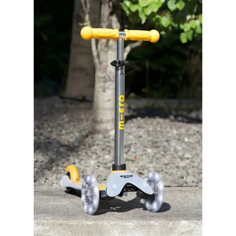 Micro Mini Deluxe Flux LED Scooter by MICRO with gray frame, yellow handlebars, and translucent wheels