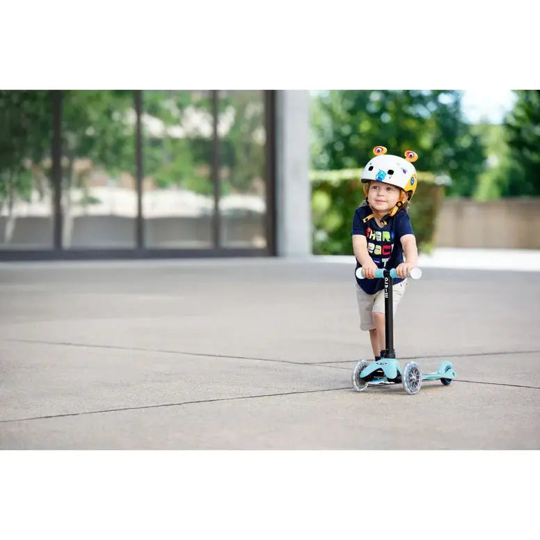 Micro Mini2Grow Deluxe LED scooter in blue; toddler rider outdoors wearing helmet manages the three-wheel scooter.