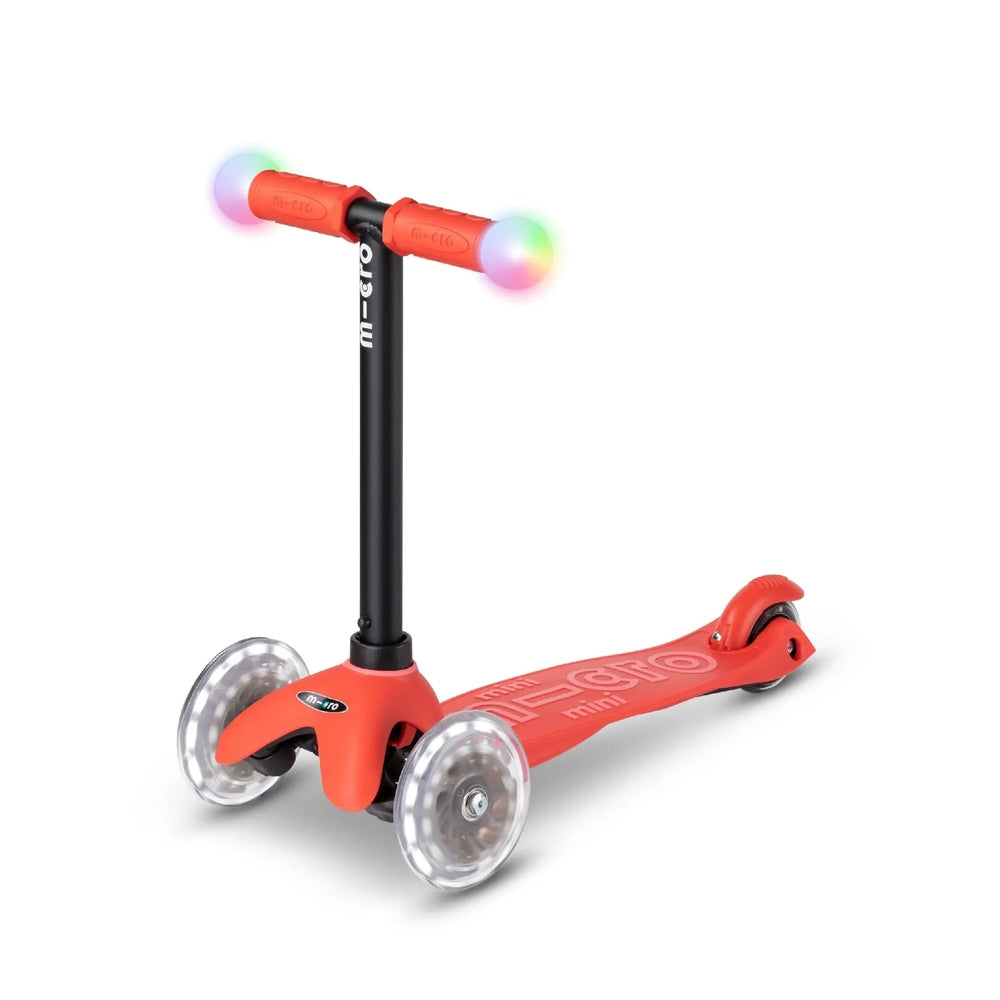 Micro Mini2Grow Deluxe LED scooter with red frame and rainbow LED handlebars, rolling on its three wheels.