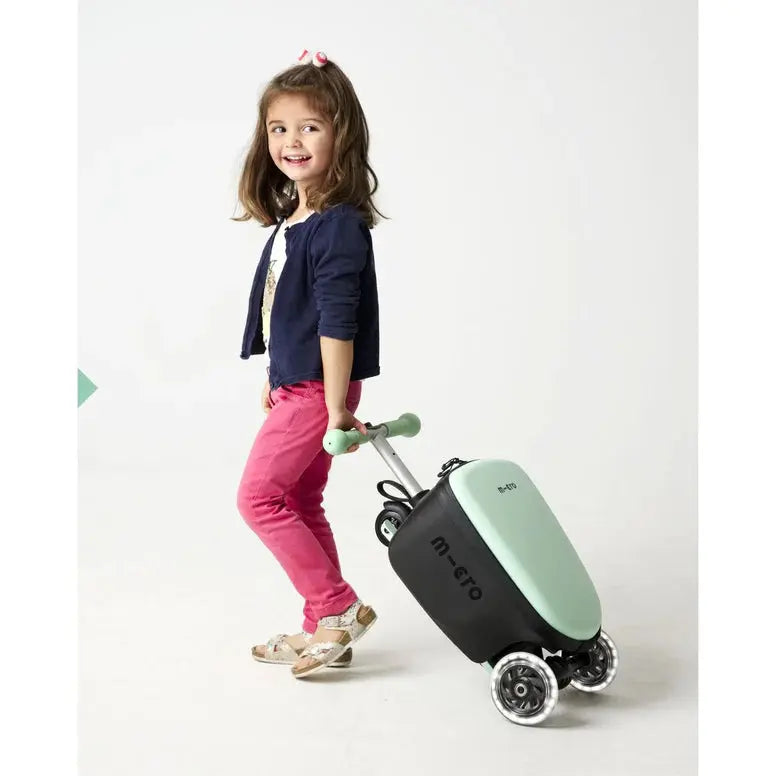 Micro Scooter Junior Luggage Mint suitcase with mint lid and black body being pulled by a smiling girl on wheels.