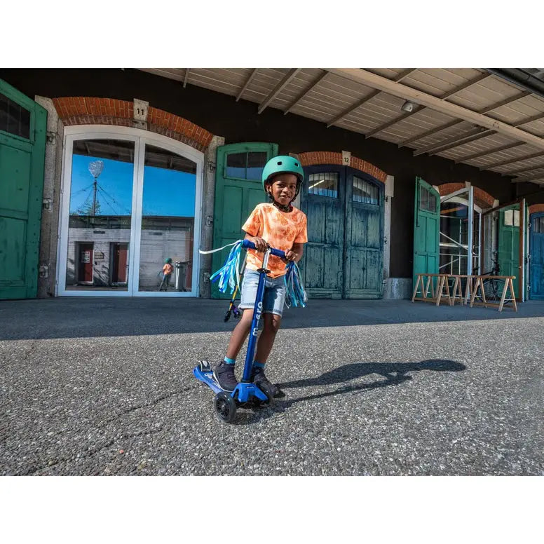 Micro Scooter Streamers: a child rides a blue MICRO scooter with blue streamers, wearing a teal helmet.
