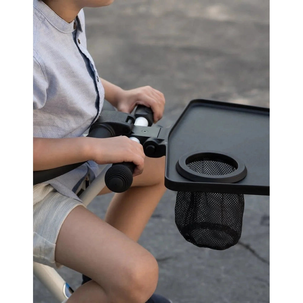 MICRO Micro Trike Table & Loop accessory on a toddler riding toy; black tray with cup holder and mesh pouch