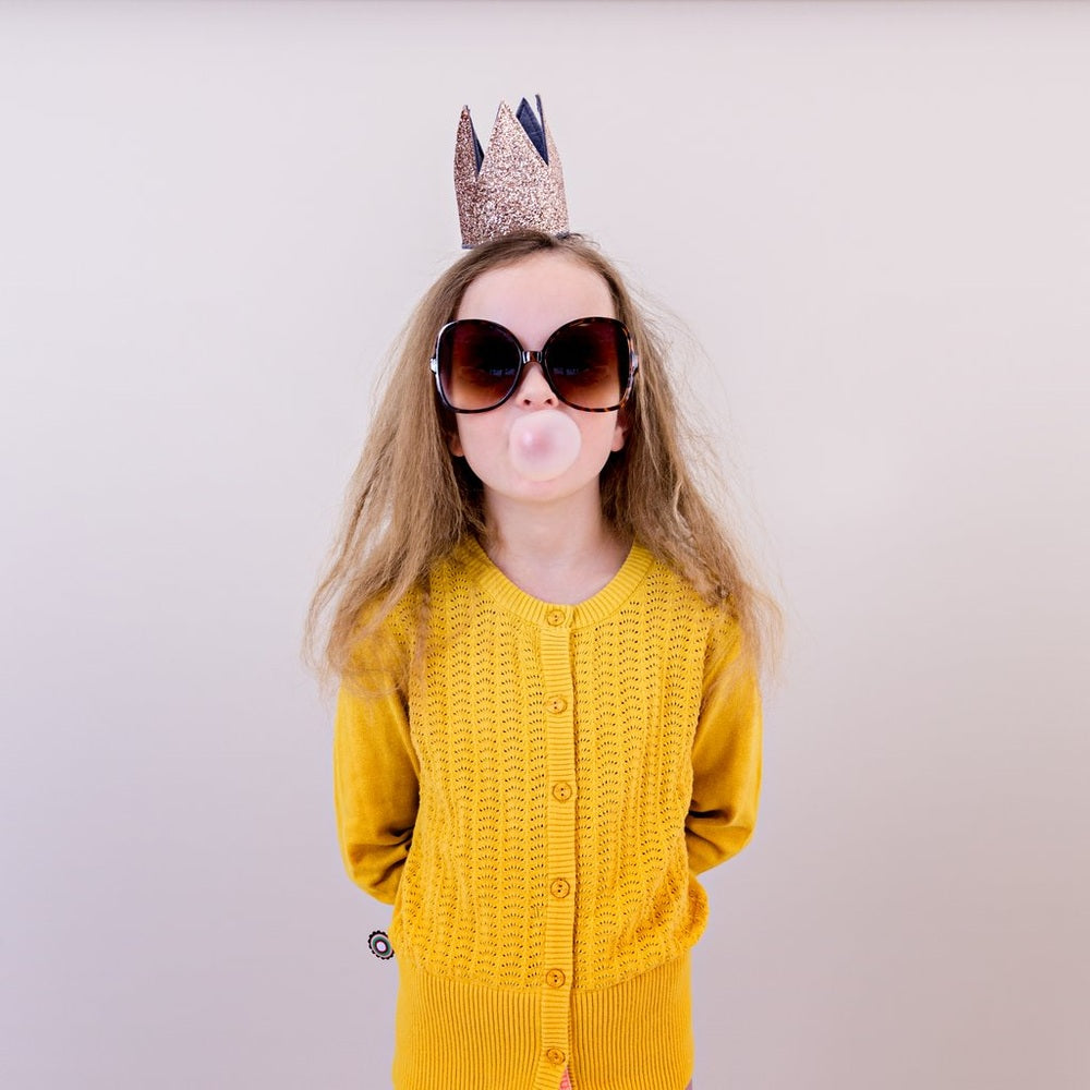 Mimi & Lula Glitter Crown Alice Gold worn by a child with oversized sunglasses and a yellow cardigan
