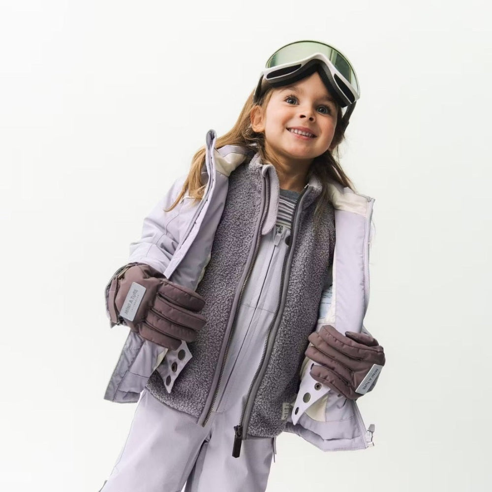 Mini A Ture Matadane Ski Tech Jacket Grs Purple Raindrops worn by a smiling girl zip-upping to reveal soft fleece lining.