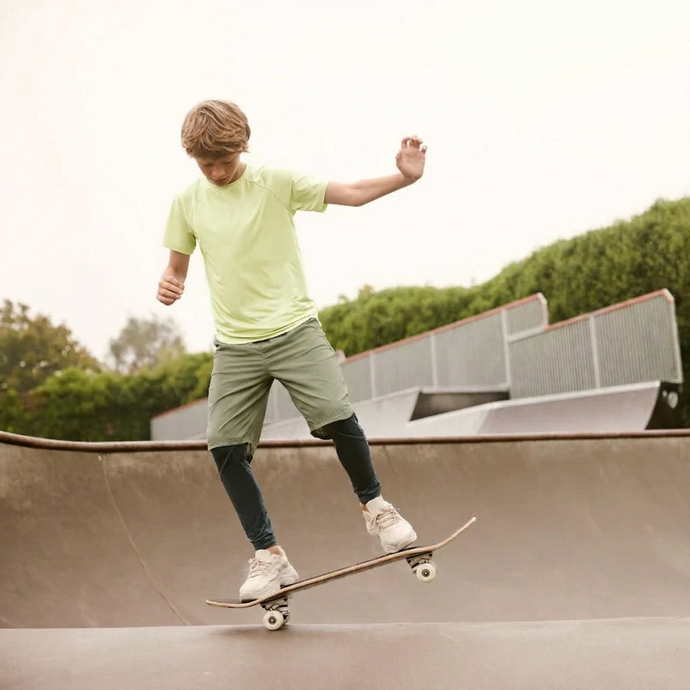 Person skateboarding on a ramp at a skate park with greenery in the background