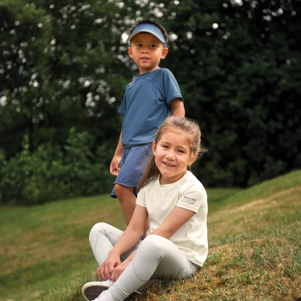 MINI A TURE Matlois SS T-Shirt Papyrus White: smiling girl sits on grass in a white short-sleeve tee.