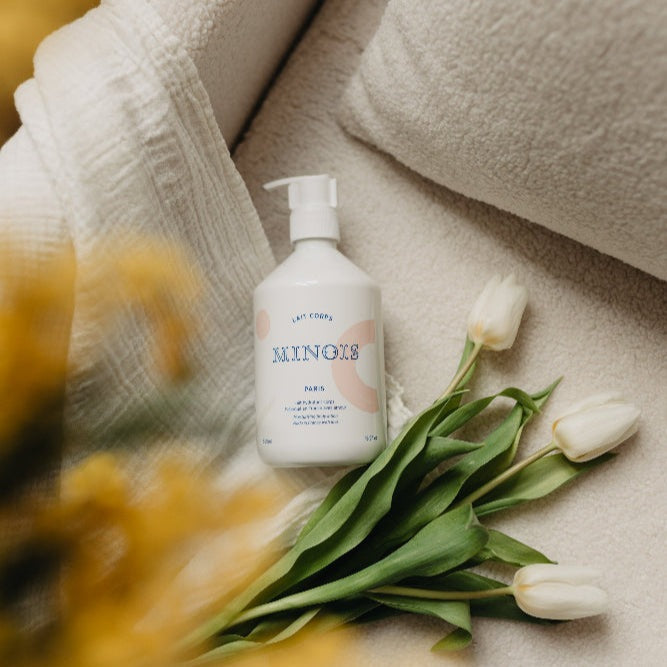 Minois Paris body lotion bottle 500 ml with white pump, pastel label, beside towels and white tulips