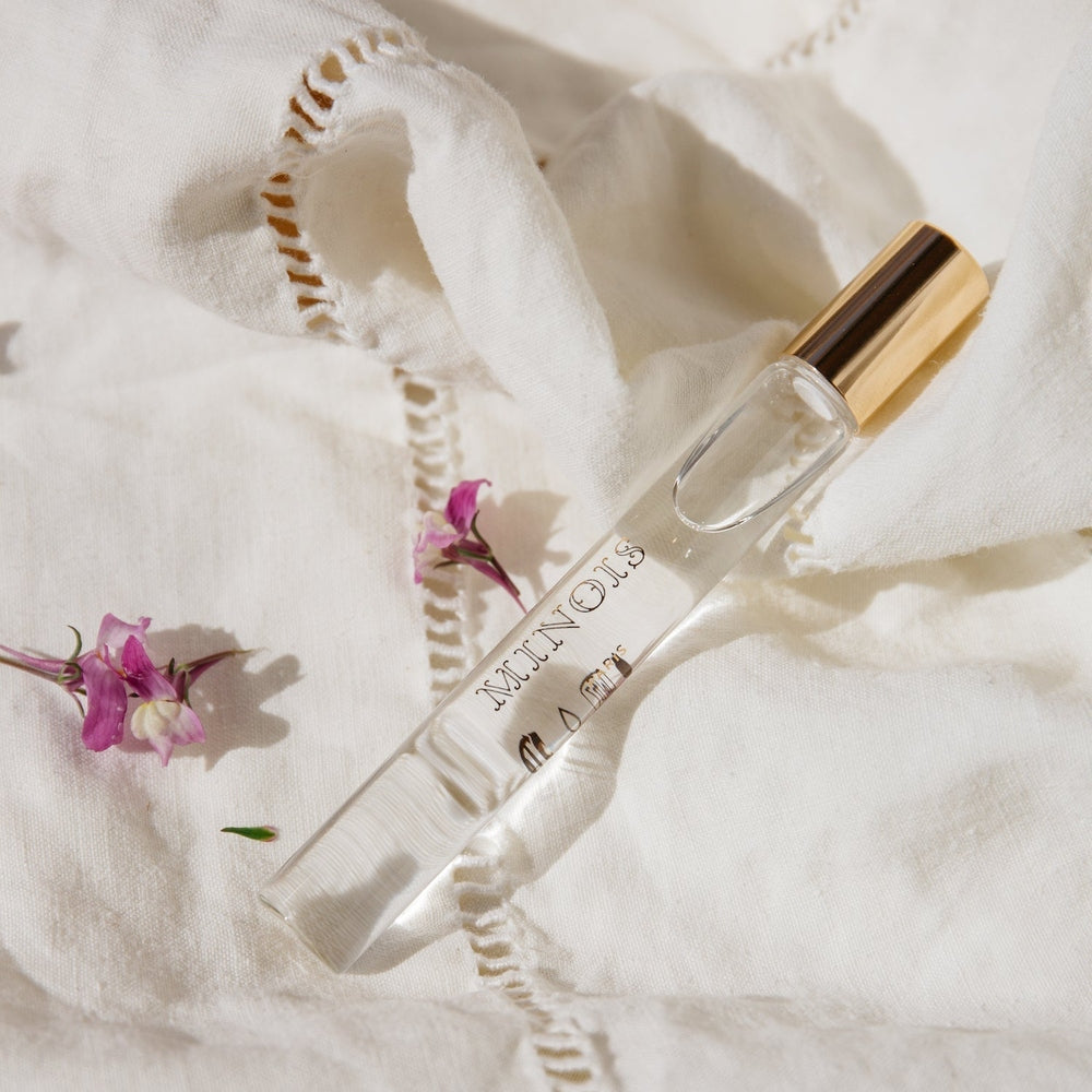 Minois Paris Eau de Toilette roll-on, 10 ml, clear glass bottle with gold cap on white linen.