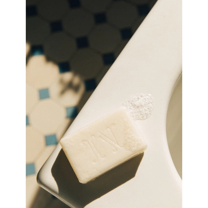 Minois Paris Gentle Soap bar, white with embossed logo, resting on a white bathroom surface