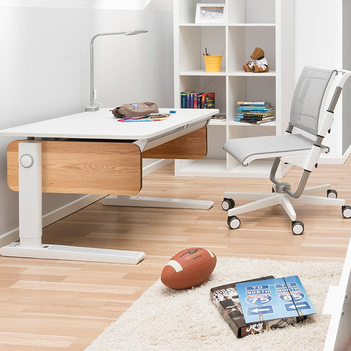 Moll Champion Height Adjustable Desk Front Up, white top with wood sides, shown at ergonomic height beside a rolling chair.