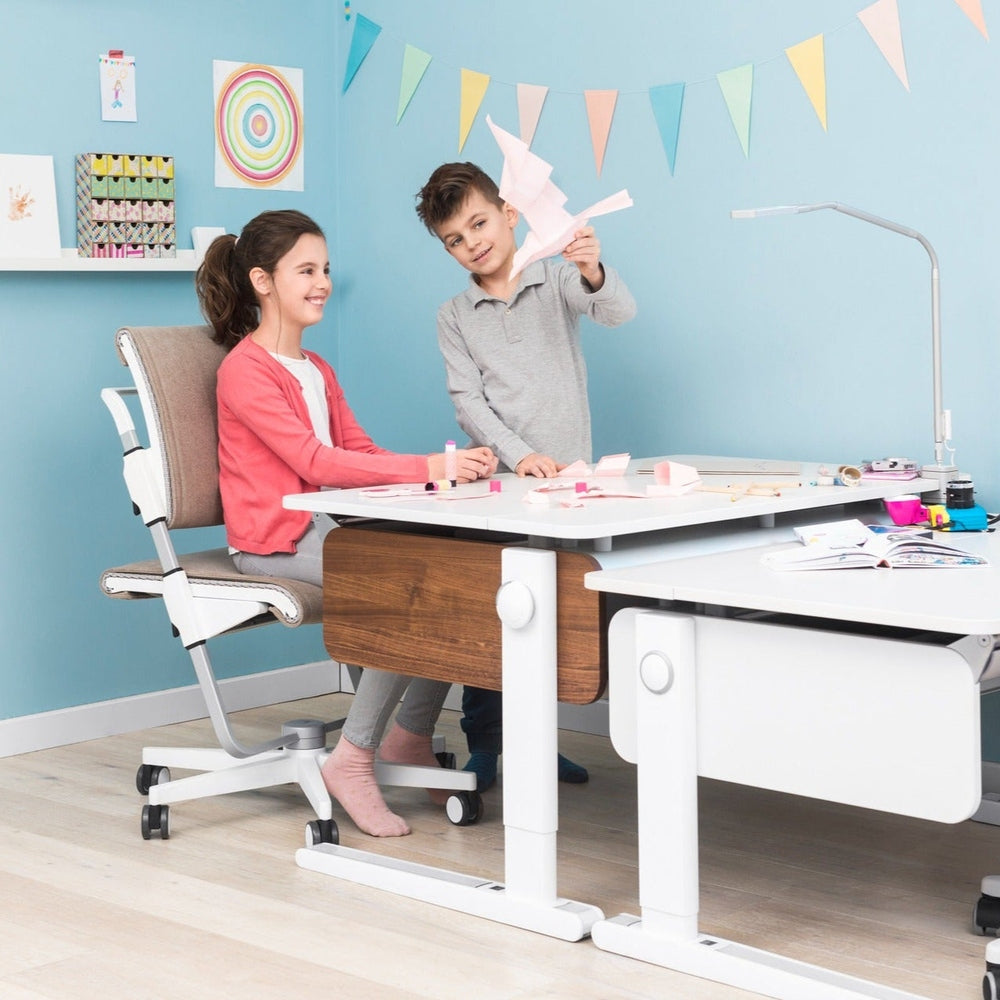 MOLL Champion Height Adjustable Desk Front Up, white frame with wood drawer; kids craft at different heights to show adjustability.
